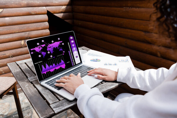 обрезанный вид африканского фрилансера с помощью ноутбука с графиками и графиками
 