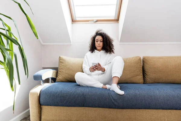 Chica Americana Africana Rizada Usando Teléfono Inteligente Sentado Sofá Casa —  Fotos de Stock