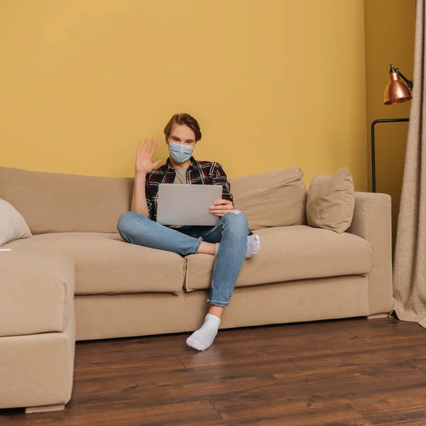 Mann Mit Medizinischer Maske Winkt Bei Videoanruf Wohnzimmer — Stockfoto