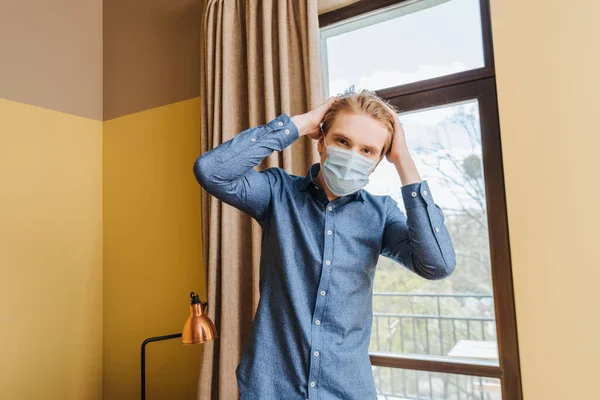 家で髪に触れる医療用マスクの若者 — ストック写真