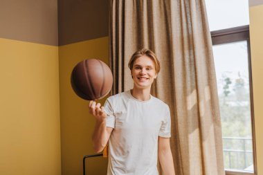 Evde basketbola bakan mutlu bir adamın seçici odak noktası, karantina konseptinin sonu.
