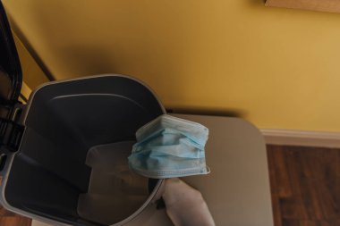 cropped view of man near medical mask in trash can, end of quarantine concept  clipart