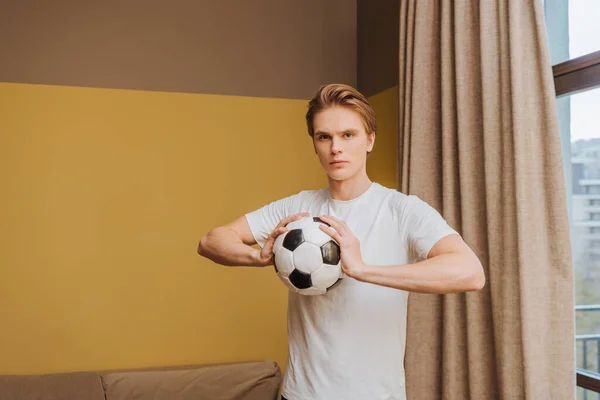 handsome man holding football at home, end of quarantine concept