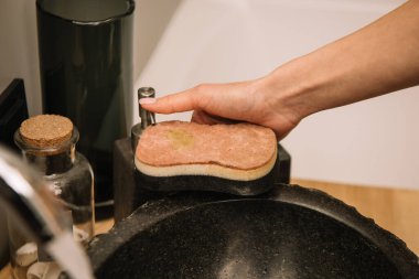 Siyah lavabonun yanında sünger tutan kadının kısmi görüntüsü