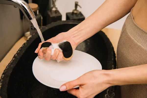 スポンジで白いプレートを洗う女性のクロップドビュー — ストック写真
