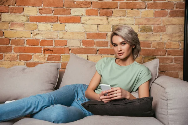 Atraente Mulher Confiante Sentado Sofá Conversando Smartphone Olhando Para Câmera — Fotografia de Stock