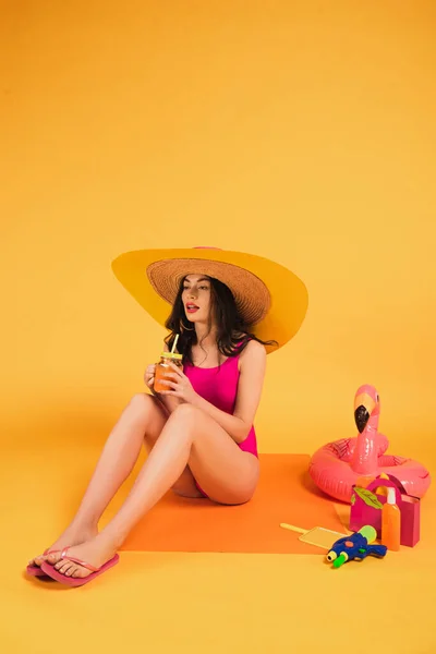 지푸라기 모자를 수영복을 주황색 주스를 여자가 부풀릴 수있는 반지와 근처에서 — 스톡 사진