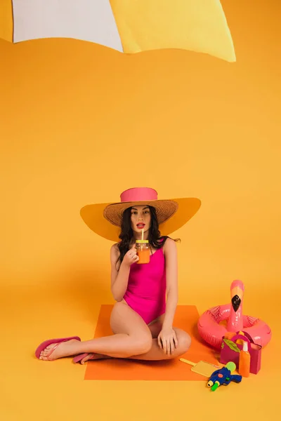 Atrakcyjna Dziewczyna Słomkowym Kapeluszu Kostiumie Kąpielowym Trzymająca Szkło Sokiem Pomarańczowym — Zdjęcie stockowe