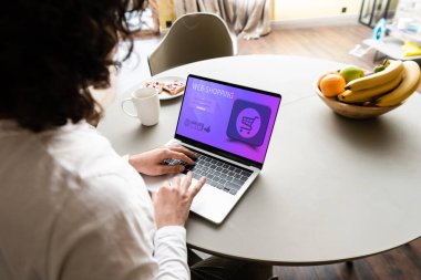Serbest çalışanın, kahve fincanı, tost ve taze meyve ekran ekranında web alışveriş sitesi ile dizüstü bilgisayar kullanmasının arka planı