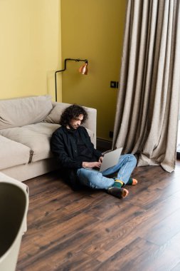 Evde dizüstü bilgisayar kullanan yakışıklı adamın seçici odak noktası. 