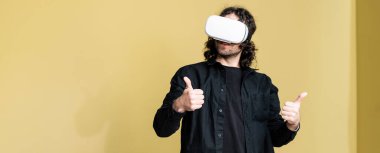 VR kulaklıklı bir adamın panoramik görüntüsü evde jest gibi görünüyor. 