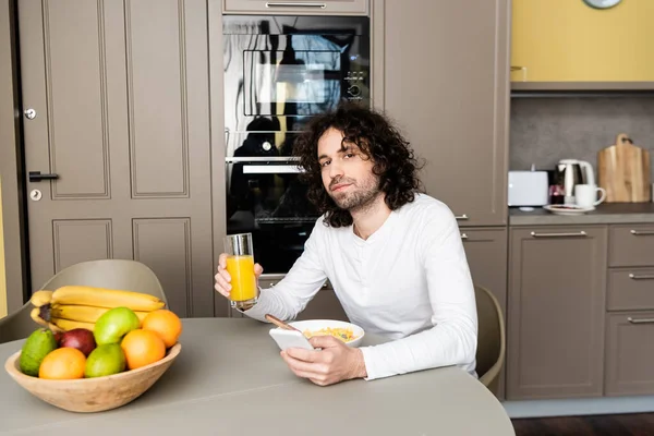 Handsome Man Looking Camera While Holding Orange Juice Using Smartphone — Stock Photo, Image