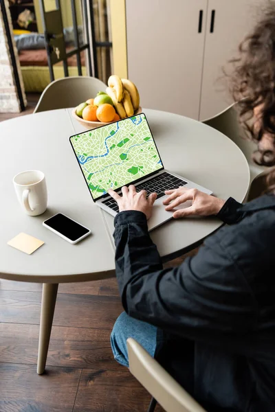 自由撰稿人在智能手机 咖啡杯 粘贴笔记和水果附近使用带有地图的笔记本电脑的背景图 — 图库照片