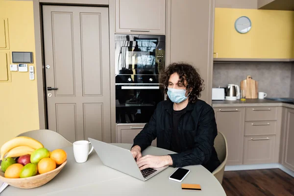 Hombre Máscara Médica Utilizando Ordenador Portátil Cerca Teléfono Inteligente Tarjeta — Foto de Stock