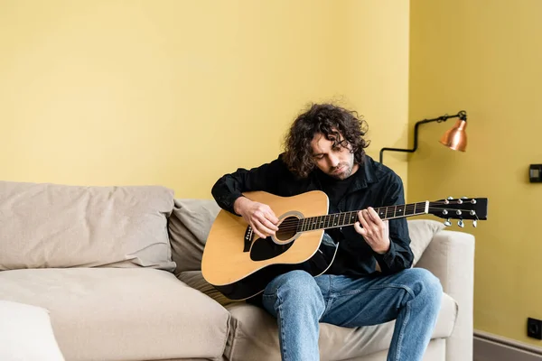 Snygg Man Som Spelar Akustisk Gitarr Soffan Vardagsrummet — Stockfoto