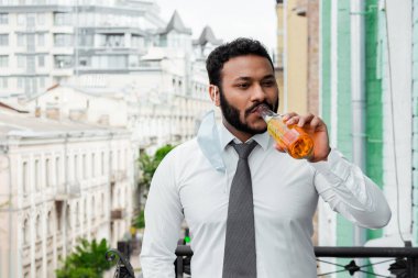 Tıbbi maskeli, bira içen sakallı Afrikalı Amerikalı adam. 