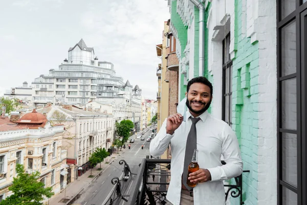 Hombre Afroamericano Feliz Tocando Máscara Médica Sosteniendo Botella Cerveza Balcón — Foto de Stock