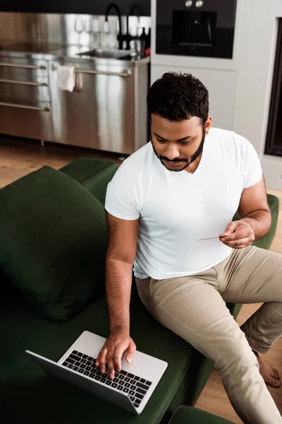 Hombre Afroamericano Sosteniendo Tarjeta Crédito Cerca Del Ordenador Portátil Mientras —  Fotos de Stock