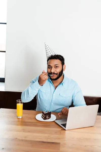 African American Man Party Cap Eating Tasty Birthday Cake Laptop — Stock Photo, Image