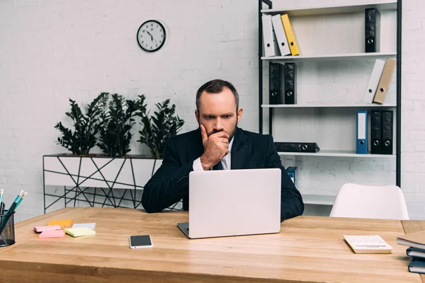 Portrait of concentrated businessman working on laptop at workplace in office — Stock Photo