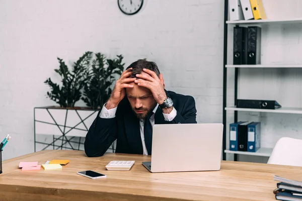 Retrato del empresario estresado sentado en el lugar de trabajo con el ordenador portátil en la oficina - foto de stock