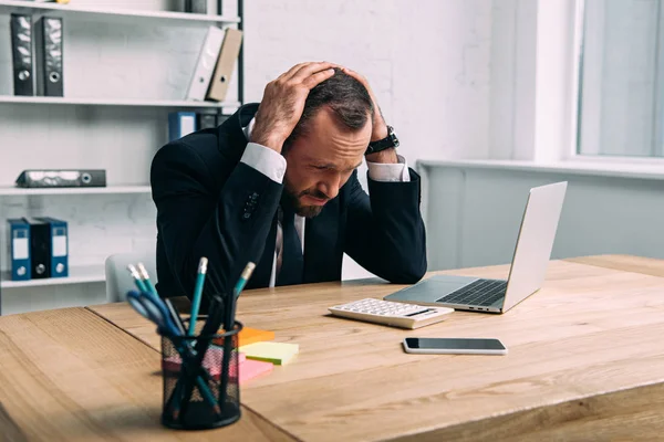 Retrato del empresario estresado en el lugar de trabajo con el ordenador portátil en la oficina - foto de stock