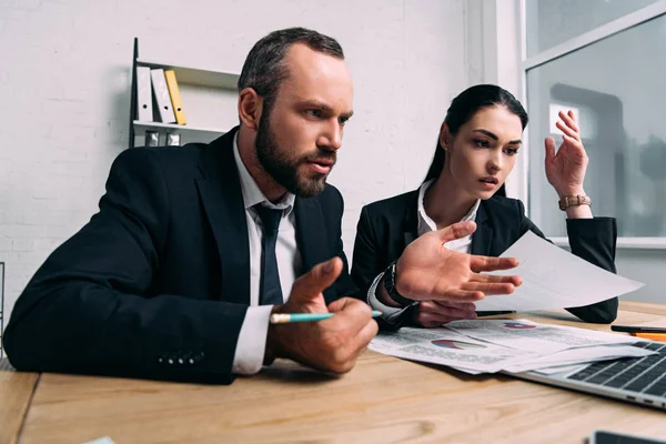 Vista laterale degli uomini d'affari stressati sul posto di lavoro con laptop in ufficio — Foto stock