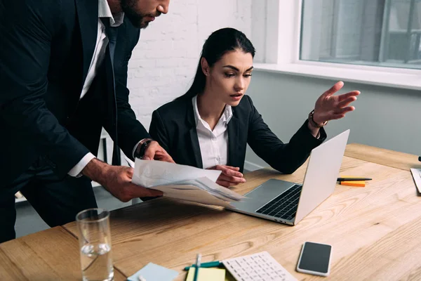 Plan recadré de femme d'affaires concentrée et collègue sur le lieu de travail avec ordinateur portable au bureau — Photo de stock