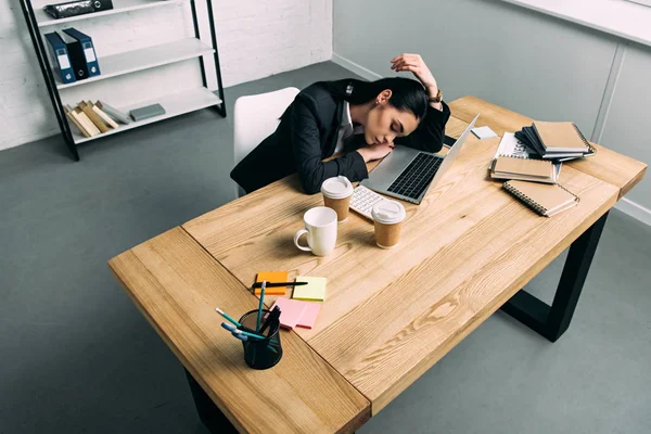 Blick aus der Vogelperspektive auf eine überlastete Geschäftsfrau, die mit Laptop und Coffee to go im Büro schläft — Stockfoto