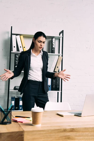 Portrait of overworked businesswoman standing at workplace with laptop in office — Stock Photo