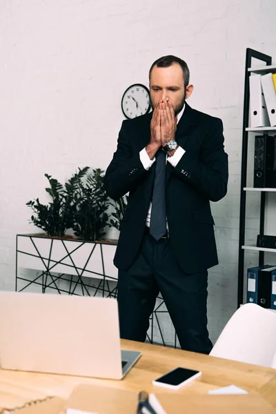 Stressed businessman in suit standing at workplace in office — Stock Photo