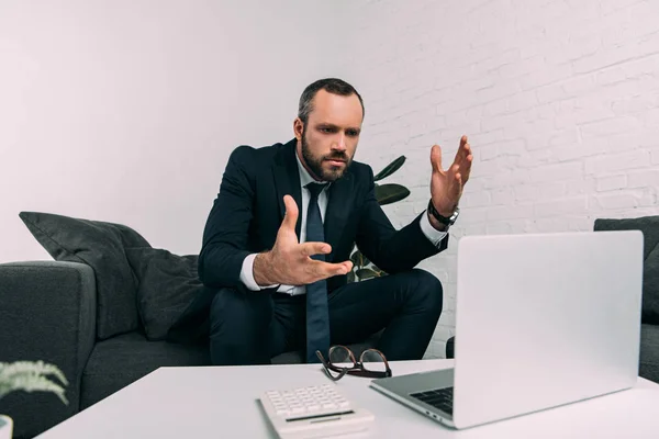 Retrato de empresário estressado em terno olhando para laptop na mesa de café no escritório — Fotografia de Stock