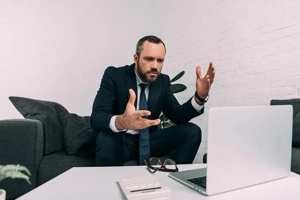 Retrato de empresario estresado en traje mirando el ordenador portátil en la mesa de café en la oficina - foto de stock