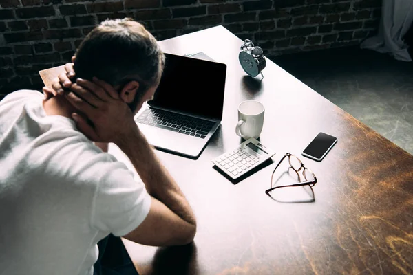 Vue grand angle de jeune homme déprimé avec ordinateur portable sur la table — Photo de stock