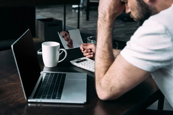 Close-up shot of depressed young man holding photo of ex-girlfriend — Stock Photo