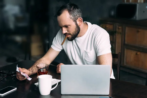 Young man smoking cigar and looking at crumpled photo of ex-girlfriend — Stock Photo