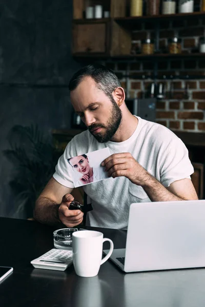 Depressed young man burning photo of ex-girlfriend at home — Stock Photo