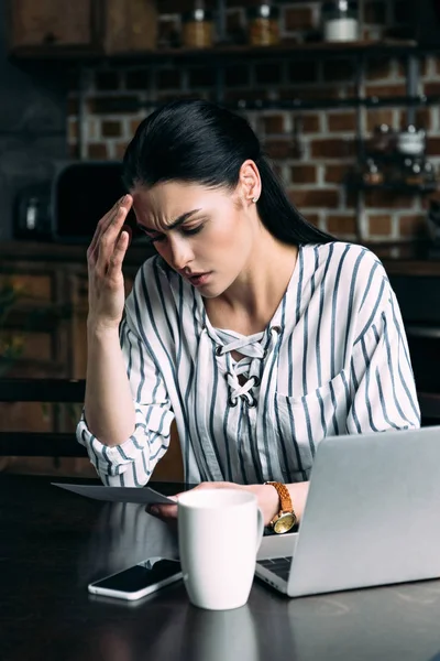 Young sad woman sitting on kitchen and looking at photo — Stock Photo