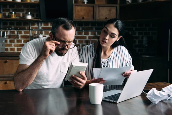 Joven pareja contando facturas juntos en casa - foto de stock