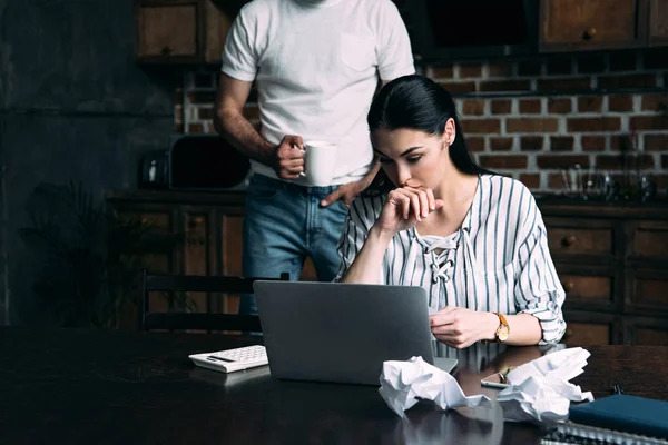 Stressé jeune femme compter les factures tandis que son mari debout derrière — Photo de stock