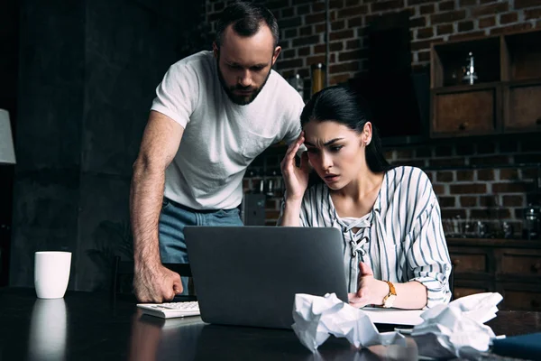 Overstressed young couple counting tax at home on kitchen — Stock Photo