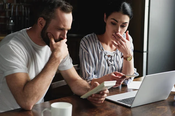 Jeune couple déprimé comptant les impôts et les factures avec ordinateur portable et calculatrice — Photo de stock