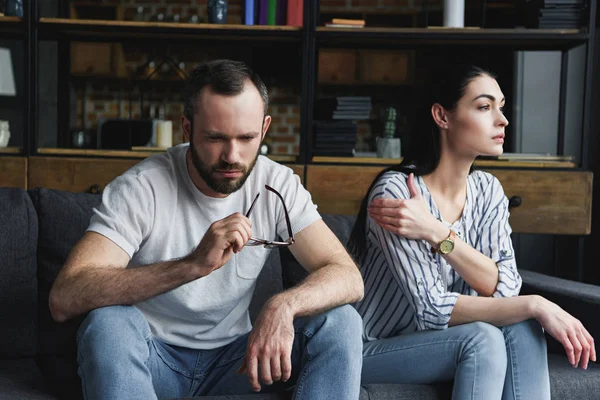 Triste couple assis sur canapé à la maison après la querelle et regardant loin — Photo de stock