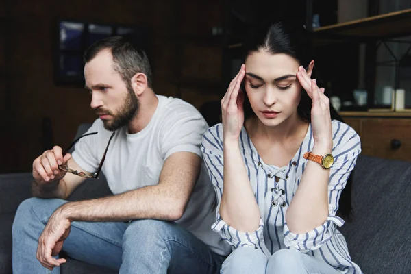 Sad young couple sitting on sofa at home after quarrel — Stock Photo