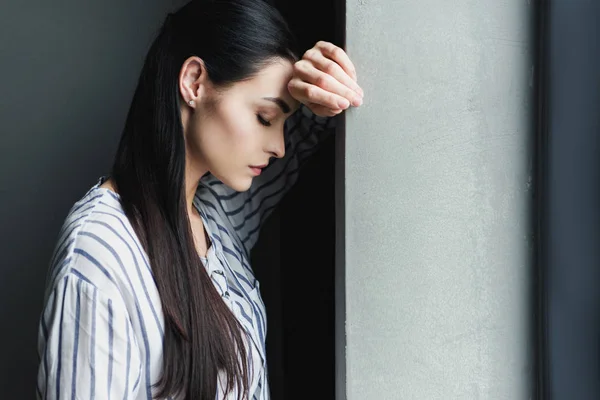 Вид збоку депресії молода жінка спирається на стіну із закритими очима — стокове фото