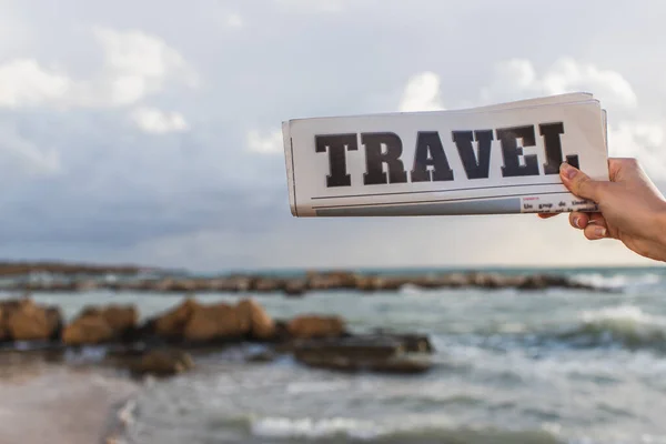 Vista recortada de la mujer sosteniendo periódico de viaje cerca del mar - foto de stock