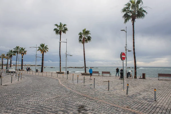 PAPHOS, CYPRUS - MARCH 31, 2020: sea shore with palm trees near people on street — Stock Photo