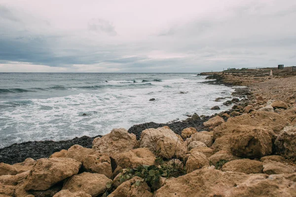 Costa tranquilla con pietre vicino al mare blu — Foto stock