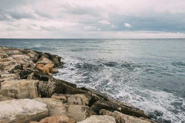 Costa tranquila con rocas cerca del mar Mediterráneo contra el cielo nublado - foto de stock