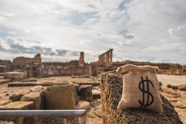 Sacchetto di denaro con il simbolo del dollaro vicino alle rovine dell'antica casa di Teseo — Foto stock